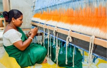 A woman participant of Prantik program weaving cloth in a workshop